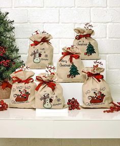 six bags with christmas designs on them sitting next to a small tree