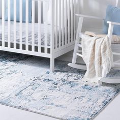 a baby's room with a rocking chair, crib and rug on the floor