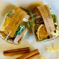 two glass jars filled with different types of spices and herbs on top of a white cloth