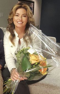 a man and woman sitting on a couch holding flowers