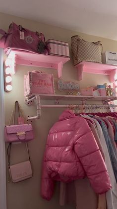 there is a pink jacket hanging on the wall next to some bags and purses