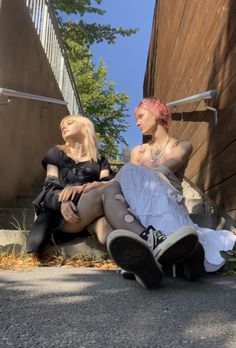 two women sitting on the ground next to each other with their hair dyed pink and black