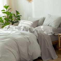 a bed sitting next to a window covered in white sheets and pillows with a clock hanging on the wall above it