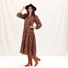 Add a splash of joy to your wardrobe with the Black Spice Madine Drop Waist Maxi Dress! Crafted from 100% cotton, this dress offers a delightfully comfortable fit that drapes beautifully. The vibrant pattern in warm spice tones is both eye-catching and stylish, perfect for making a statement. The full-length sleeves with elastic cuffs add a touch of charm and practicality, while the V-neck mandarin collar gives it an elegant touch. The dress features playful details like long decorative tassels Fall Season Relaxed Fit Maxi Dress, Relaxed Fit Fall Maxi Dress, Flowy Cotton Maxi Dress For Fall, Fall Floral Print Orange Maxi Dress, Winter Floral Print Cotton Dress, Brown Relaxed Fit Dress For Fall, Winter Cotton Floral Print Dress, Winter Cotton Dress With Floral Print, Cotton Midi Dress For Fall