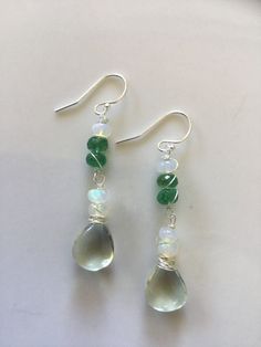 I love the colour combination of these stones. Heart shape smooth green amethyst, with flashing rondelle moonstones and untreated, natural emeralds. The wiring is sterling silver. The ear wires are also sterling silver but I can change them to surgical silver ones. Also, white gold is always an option however I would have to order them in. ABOUT SHIPPING- Shipping within Canada is crazy expensive. If there is any overage I will refund. I'm very limited in adding different cost of shipping betwee Green Moonstone Jewelry Gift, Green Amethyst Gemstone Earrings, Green Moonstone Round Jewelry, Handmade Green Briolette Earrings, Green Sterling Silver Crystal Earrings, Handmade Green Crystal Sterling Silver Earrings, Green Moonstone Jewelry With Natural Stones, Green Moonstone Jewelry For Healing, Green Faceted Sterling Silver Earrings