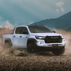 a white toyota pickup truck driving down a dirt road