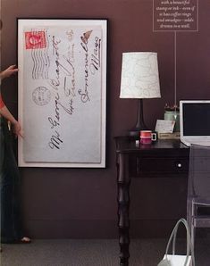 a woman standing next to a desk with a laptop computer on it and writing on the wall