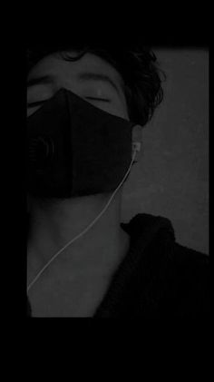 a man wearing a black face mask with earphones attached to his ears in the dark