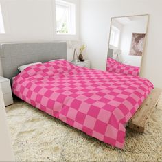 a bed with a pink checkered comforter and matching pillow cases in a white room