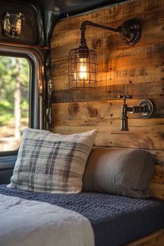 a bed in a room with wooden walls and lights on the headboard, next to a window