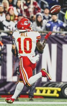 a football player catching a ball in the air with his arm extended and feet spread out