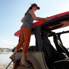 a woman standing on top of a car with a surfboard