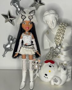 a doll with long hair standing next to a white teddy bear and silver stars on the wall