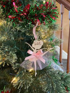 a christmas tree decorated with pink and green ornaments, bows and name on the ornament