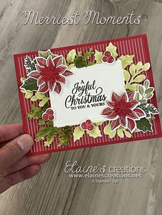 someone holding up a christmas card with poinsettis and holly leaves on it