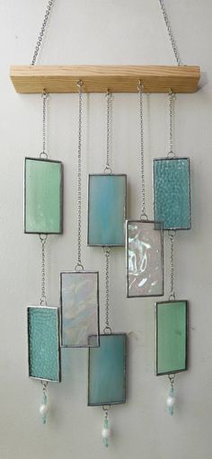 a metal and glass wall hanging on a white wall next to a wooden board with beads