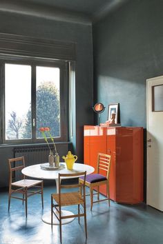 a kitchen with an orange cabinet and white table in the center, next to a window