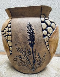 a vase that has some kind of plant on it's side and rocks in the back