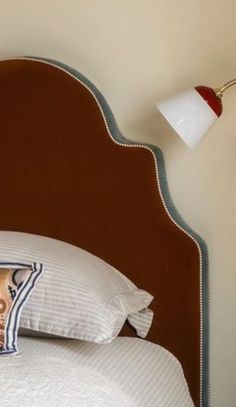 a bed with two pillows on top of it and a lamp next to the headboard