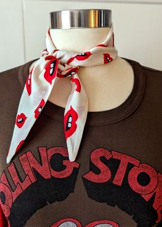 All accessories are final sale Kiss Kiss! Silk scarf tie featuring red lips on a white base. Wear it tied around your neck, as a headband, as a hat band, whatever ya like! Print placement varies per scarf. Features: Skinny scarf 100% silk White colorway with red and black lip design Handmade in LA Brand & Fabric Content: Brand: I'm With the BandMaterials: 100% silkMade in: Los Angeles, CA Approx. measurements: Approx. 33" long and 2.5" wide when laid flat