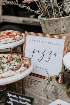 two pizzas sitting on top of white plates next to a sign that says i love you with every pizzo my heart