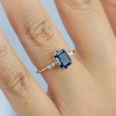 a woman's hand with a ring on it and a blue stone in the middle