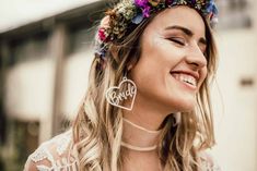 a woman with flowers in her hair smiles and wears a flower crown on her head