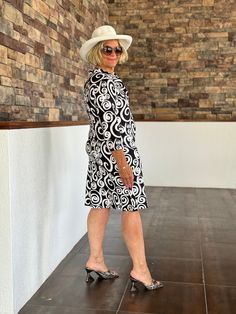 a woman in a white hat and black dress is standing on the floor with her legs crossed