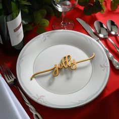 a white plate with the word hello spelled on it next to silverware and wine glasses