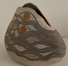 a vase is sitting on a white surface with waves and circles painted on the side