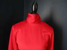 "Vintage red professional blouse from JH Collectibles. Long sleeves with thick button cuff at wrist, and buttons up back of high neck collar. Waist is tailored and defined. Padded shoulders. 100% Polyester Size 8. 20\" underarm to underarm 24\" sleeve 25.5\" length." Fitted High Neck Blouse, Formal Solid Tops For Winter, Formal High Neck Fitted Blouse, Formal Stretch Winter Tops, Fitted Winter Office Blouse, Classic Stretch Red Tops, Classic Red Stretch Tops, Fitted Solid Tops With Stand Collar, Fitted Solid Color Top With Stand Collar