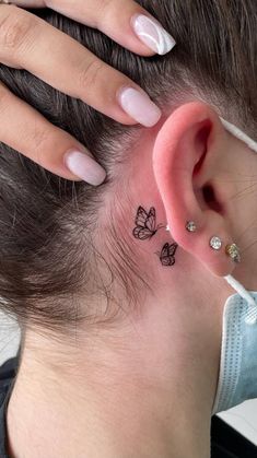 a woman's ear has a butterfly tattoo on it