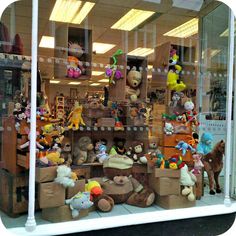 stuffed animals are displayed in the window of a toy store with lots of them on display