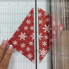 someone is cutting out a red and white snowflake pattern on a piece of fabric