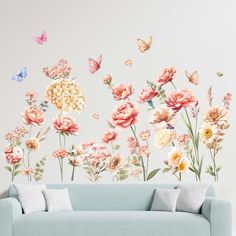 a couch sitting under a wall with flowers and butterflies on it