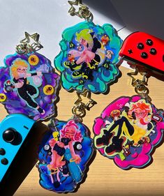 four keychains with cartoon characters on them next to a nintendo wii game controller