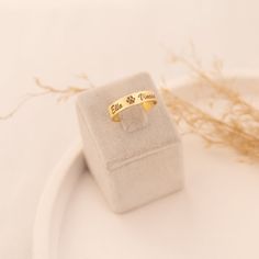 a gold ring sitting on top of a white plate next to some dried grass and a plant