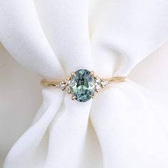 a blue diamond ring sitting on top of a white cloth