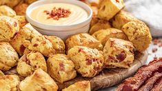 bacon and cheese rolls on a cutting board with dip in the middle