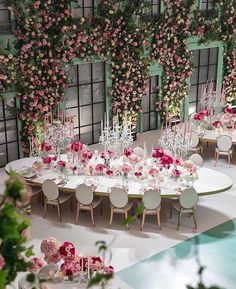 the tables are set up with white chairs and pink flowers on each table, along with greenery