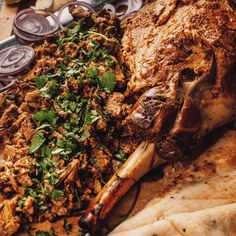 a plate full of meat and vegetables on top of a wooden table with utensils