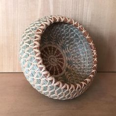 a blue and white bowl sitting on top of a wooden table next to a wall