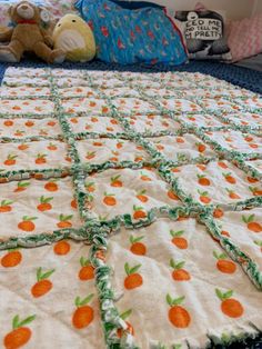 a child's bed with an orange and white quilt on it, next to a teddy bear