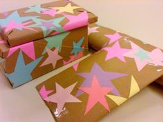 three brown boxes with pink, blue and green stars on them sitting on a table