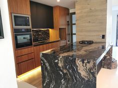 a large kitchen with marble counter tops and wooden cabinetry, along with an oven