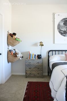 a bed room with a neatly made bed and two baskets on the wall above it