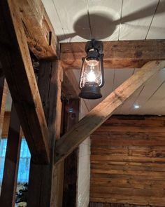 a light hanging from the ceiling in a room with wood walls and beams on it