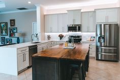 a large kitchen with stainless steel appliances and wooden counter tops, along with white cabinets