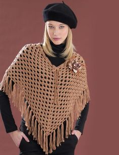 a woman wearing a brown crocheted shawl with a rose on the side