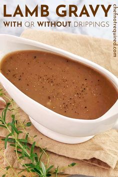 a white bowl filled with soup sitting on top of a wooden table next to a napkin